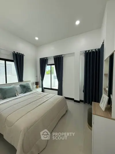 Spacious bedroom with modern decor and large windows for natural light.