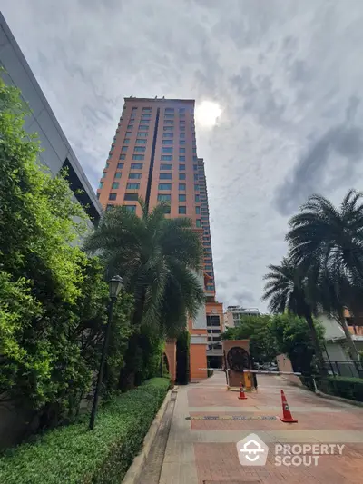 Stunning high-rise building with lush greenery and palm trees under a bright sky.