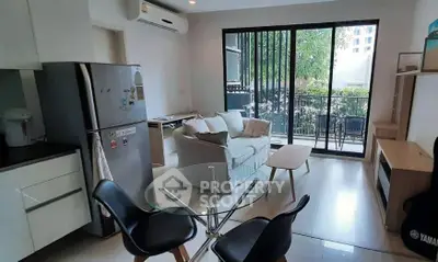 Modern living room with glass doors leading to a balcony, featuring stylish furniture and natural light.