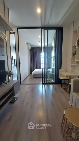 Modern apartment interior with sliding glass doors leading to a cozy bedroom, featuring stylish decor and wooden flooring.