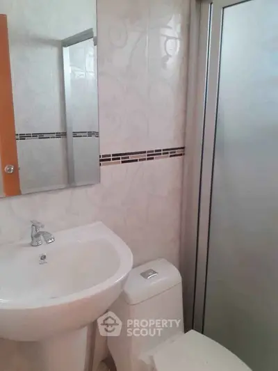 Compact bathroom with modern fixtures and frosted glass shower door.