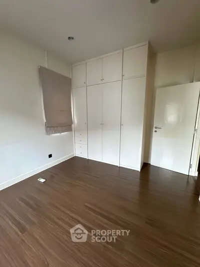 Spacious bedroom with wooden flooring and built-in wardrobe, perfect for modern living.