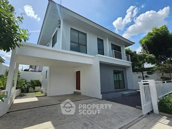 Modern two-story house with spacious driveway and lush greenery under a clear blue sky.