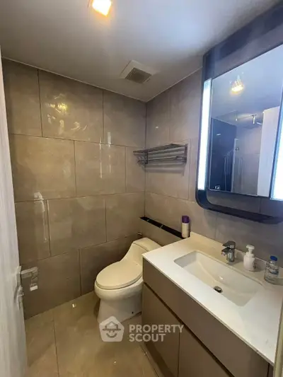 Modern bathroom with sleek fixtures and illuminated mirror in a contemporary apartment.