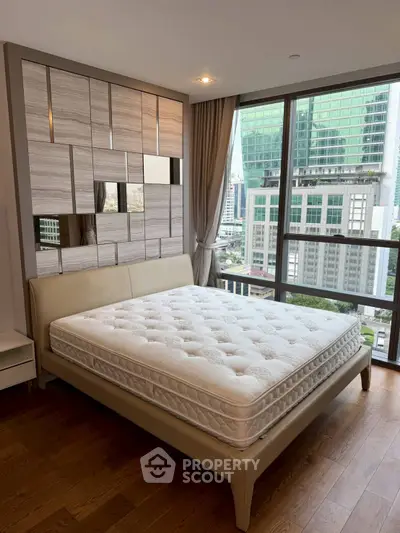 Modern bedroom with large windows and city view, featuring stylish decor and a comfortable bed.