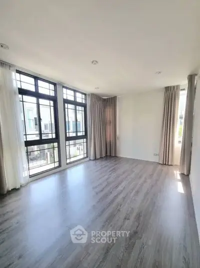Spacious empty room with large windows and elegant curtains, perfect for customization.