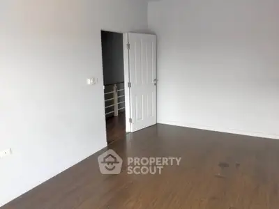 Spacious empty room with wooden flooring and white walls, ideal for customization.