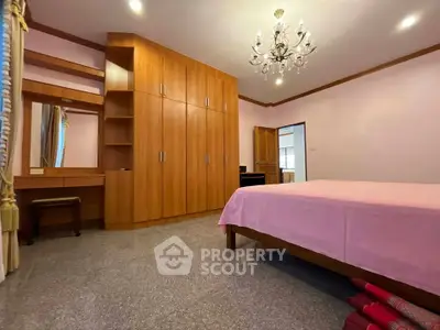 Spacious bedroom with elegant chandelier and ample wooden storage