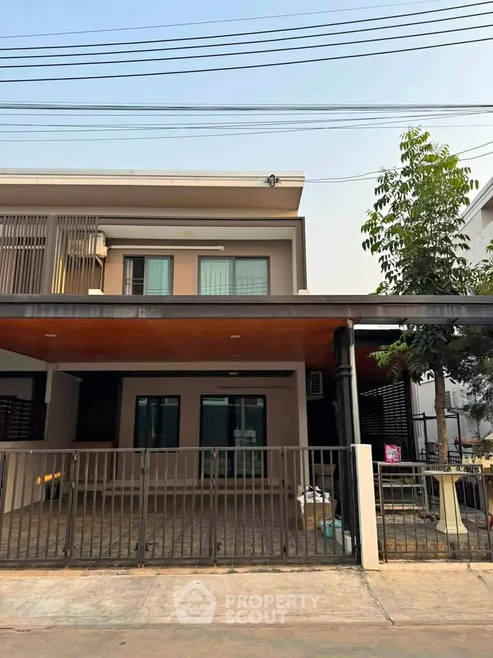 Modern two-story house with gated driveway and contemporary design in a suburban neighborhood.