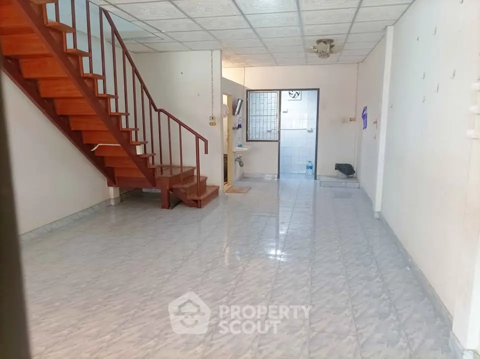 Spacious open-plan living area with wooden staircase and tiled flooring, ideal for modern living.