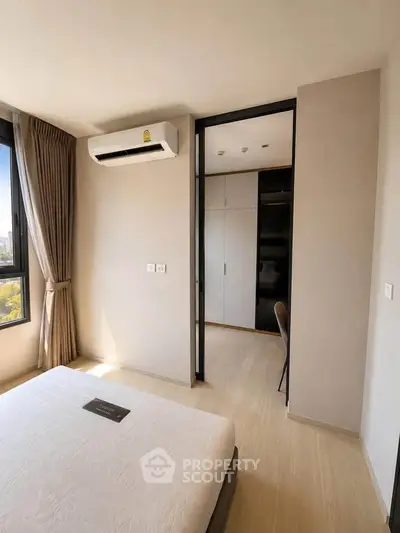 Modern bedroom with air conditioning and natural light, featuring a minimalist design and neutral tones.