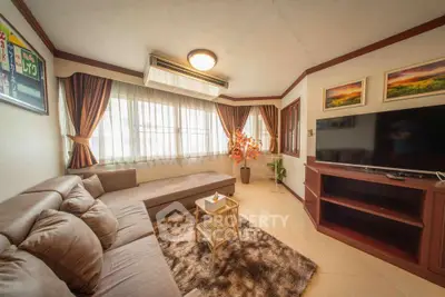 Cozy living room with sectional sofa, large window, and flat-screen TV, perfect for relaxation.