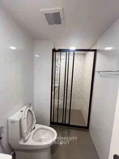 Modern bathroom with sleek shower enclosure and white tiled walls.