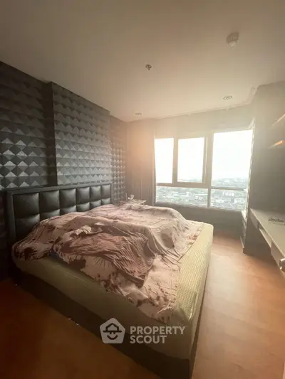 Spacious bedroom with large window offering stunning city views and modern decor.