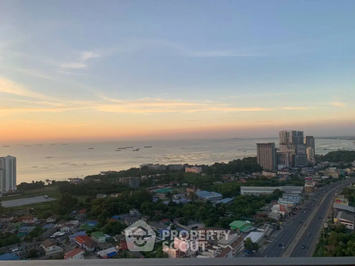 Stunning cityscape view with ocean horizon at sunset, showcasing urban living and serene coastal beauty.