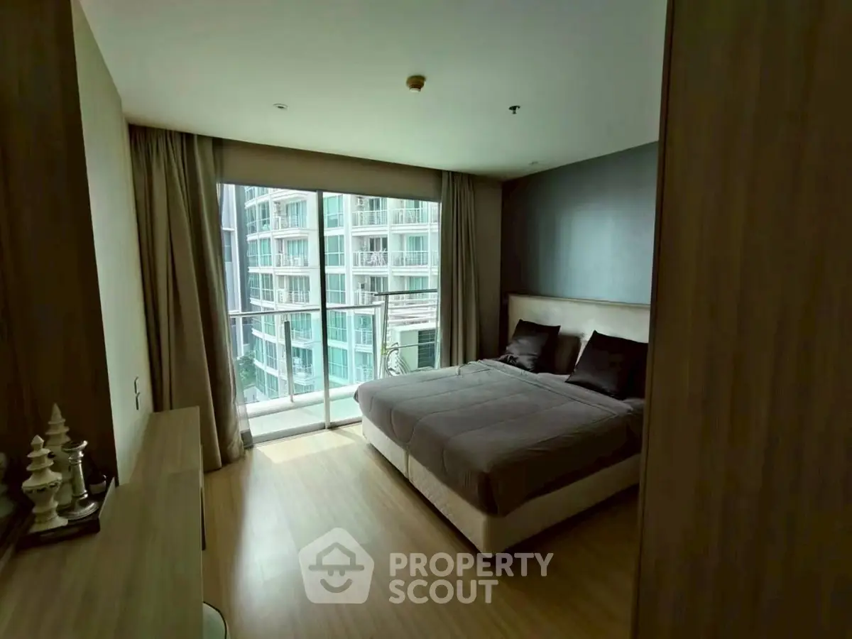 Spacious bedroom with large window and modern decor in a high-rise apartment.