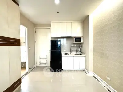 Modern compact kitchen with sleek cabinetry and appliances in a cozy apartment setting.