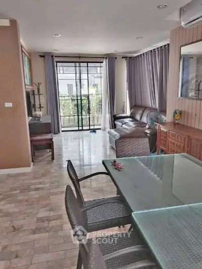 Spacious living room with glass dining table and cozy seating area, perfect for family gatherings.