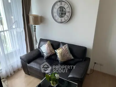 Stylish living room with leather sofa, elegant clock, and natural light