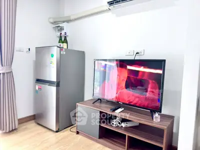 Modern living room with sleek TV setup and stainless steel fridge, perfect for urban living.