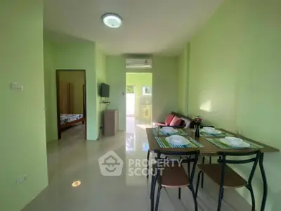 Bright green living area with dining set and view into bedroom, modern and inviting.