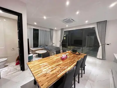 Modern open-plan living and dining area with sleek furniture and large windows.