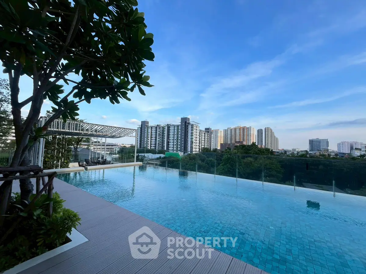 Stunning rooftop pool with panoramic city skyline views and lush greenery.