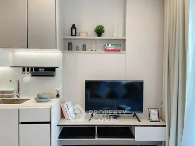 Modern living room with sleek TV setup and stylish kitchen area.