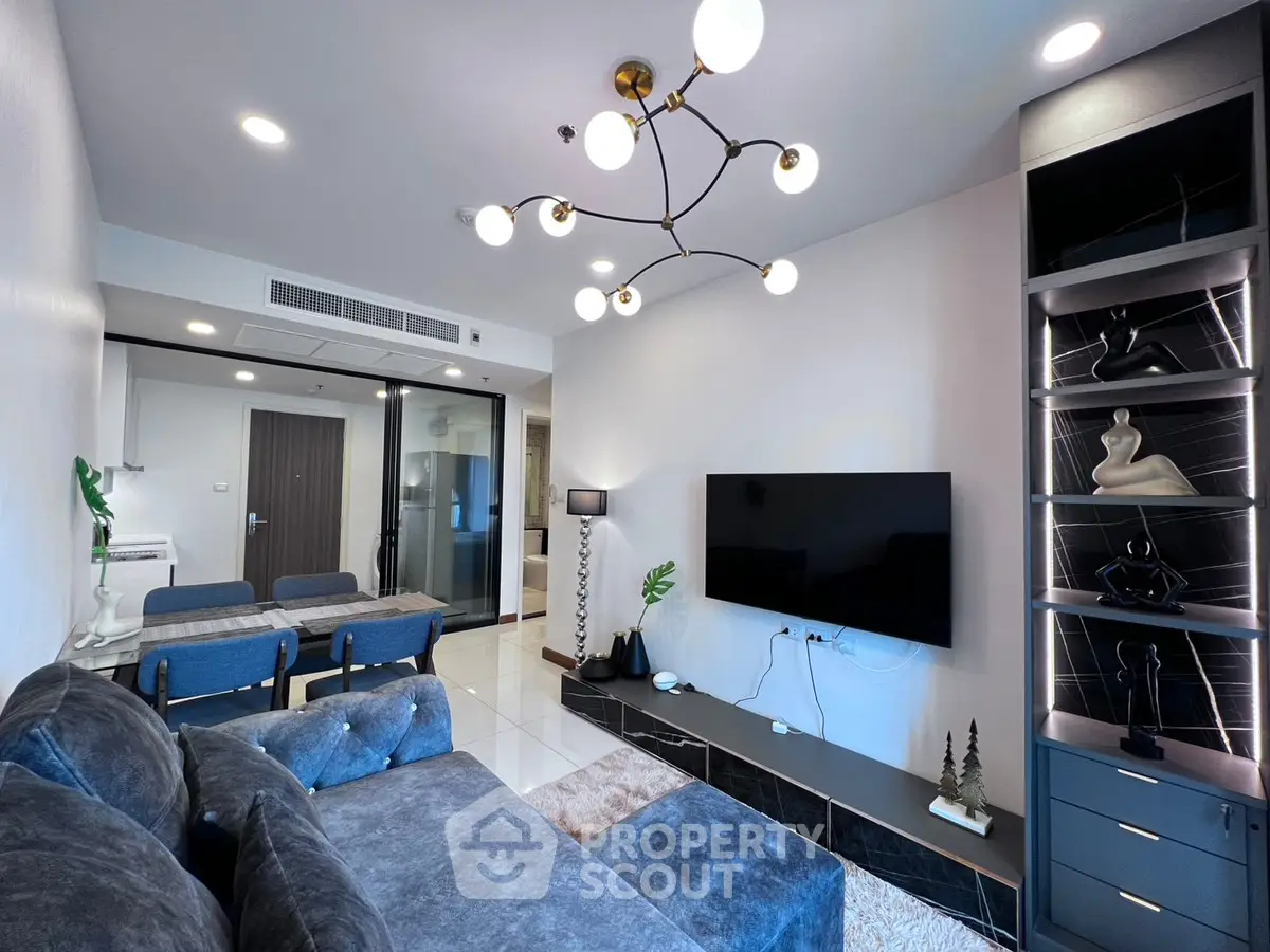 Modern living room with stylish decor and open layout, featuring a plush gray sofa and sleek entertainment center.