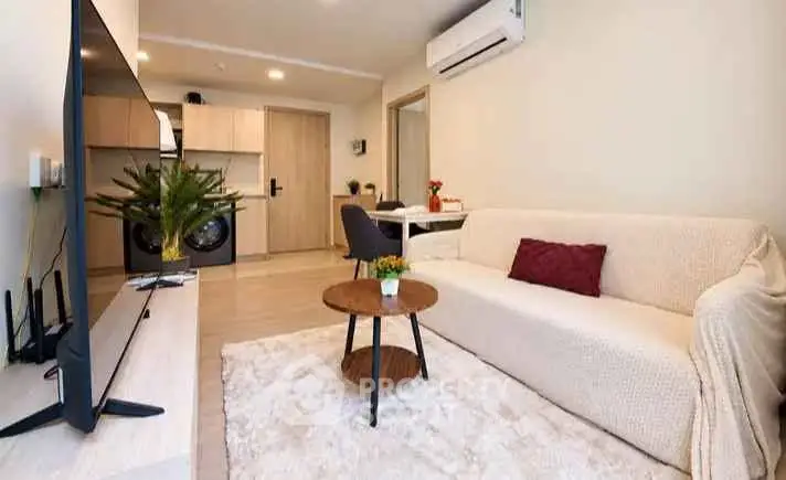 Modern living room with cozy sofa, TV, and open kitchen layout in stylish apartment.
