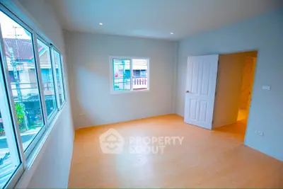 Spacious empty room with large windows and wooden flooring, perfect for customization.