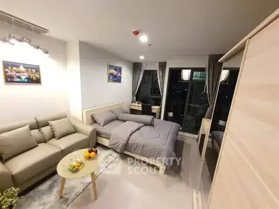 Modern studio apartment with cozy living area and bed, featuring city view.