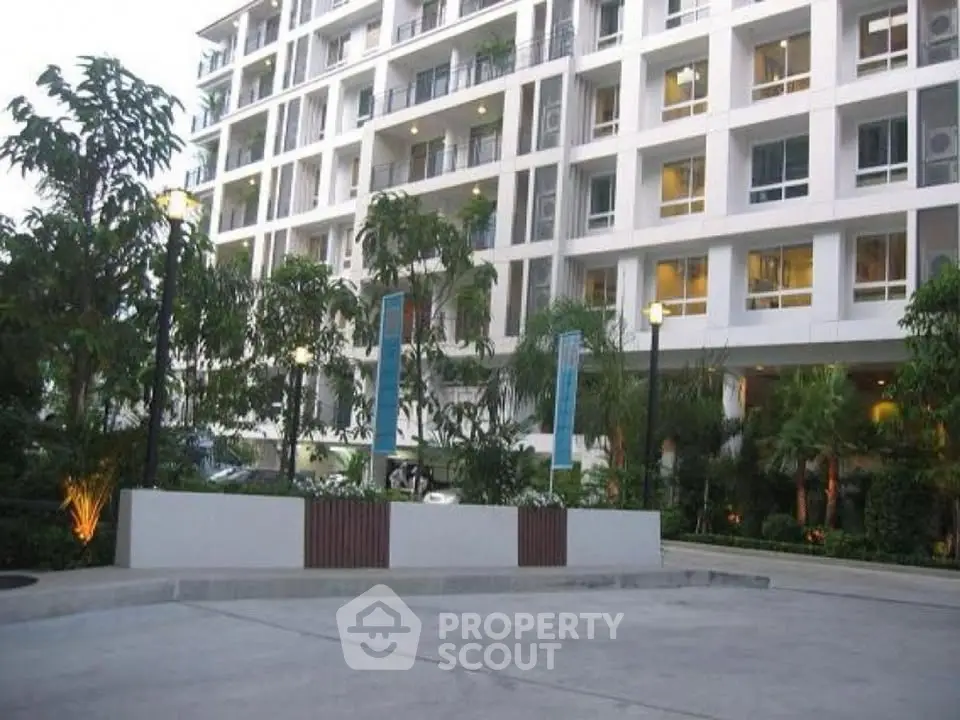 Modern apartment building with lush landscaping and spacious parking area.