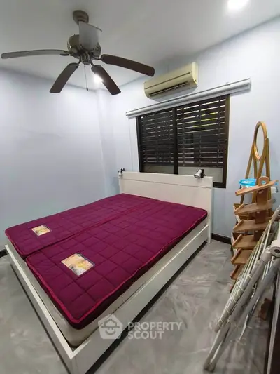 Cozy bedroom with modern ceiling fan and air conditioning, featuring a stylish bed and sleek flooring.
