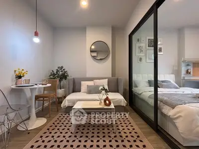 Modern studio apartment with cozy living area and stylish bedroom separated by glass partition.