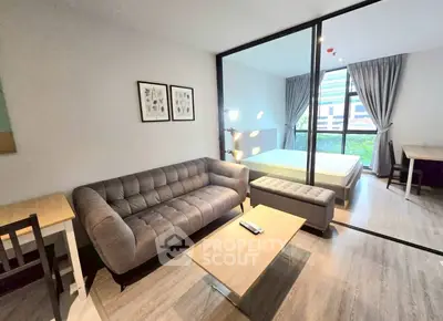 Modern studio apartment with stylish living area and bedroom separated by glass partition.