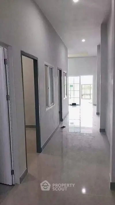 Spacious hallway with modern design and natural light leading to open living area.