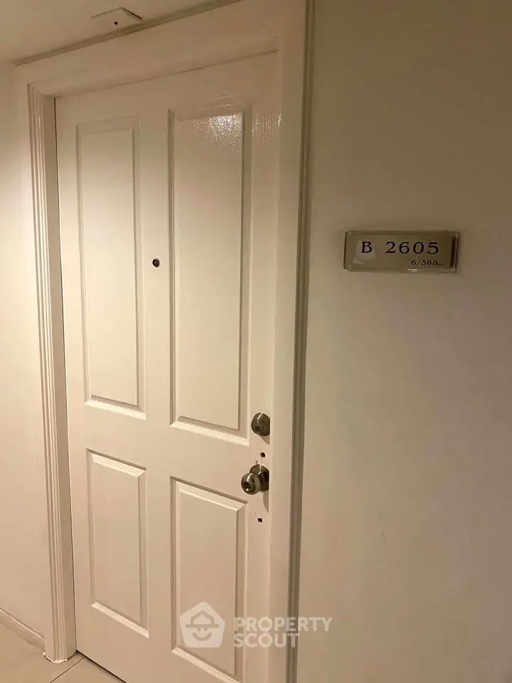 Modern apartment entrance with sleek white door and unit number plaque.