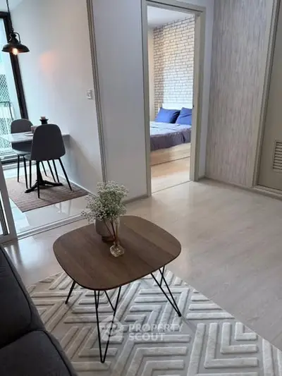 Modern open-plan living room with stylish furniture and a glimpse into a cozy bedroom.
