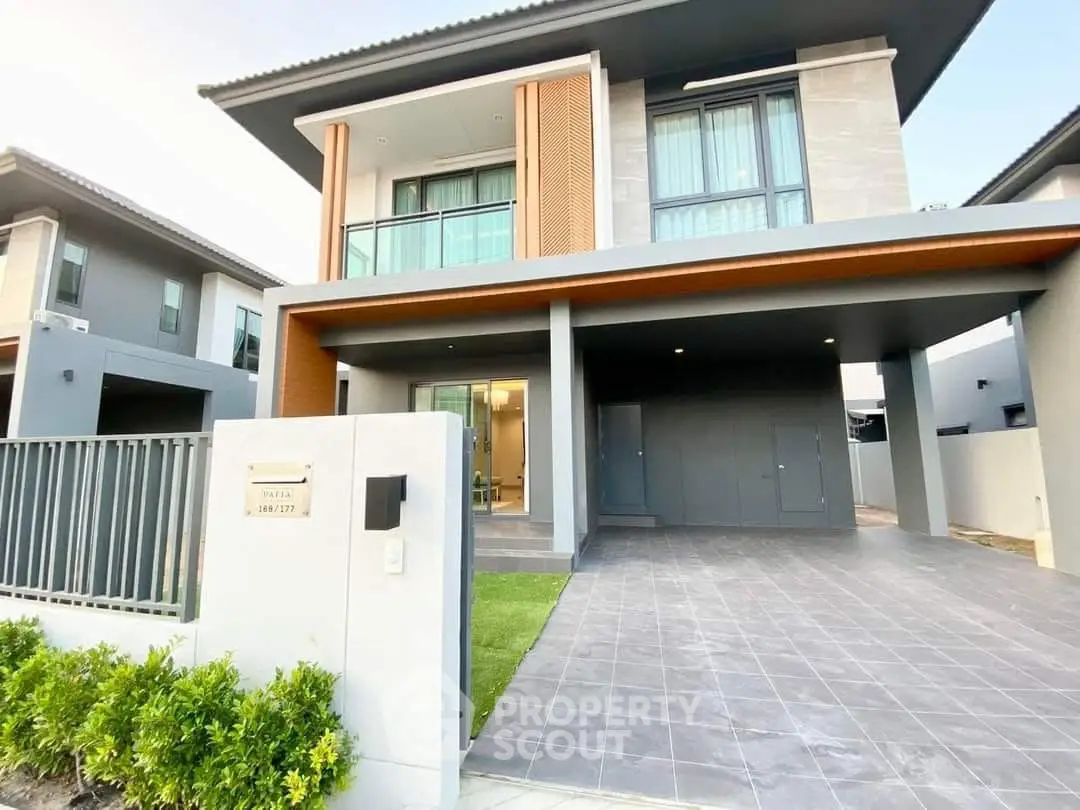 Modern two-story house with spacious driveway and sleek architectural design.