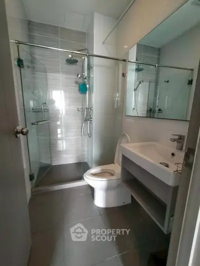 Modern bathroom with glass shower and sleek fixtures in contemporary apartment.