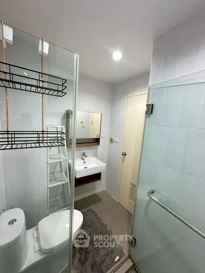 Modern bathroom with glass shower, sleek fixtures, and ample storage space.