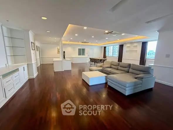 Spacious open-plan living room with elegant hardwood floors and modern furnishings in a luxury apartment.