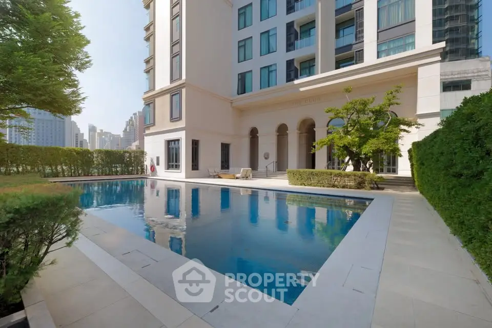 Luxurious residential building with serene pool and lush greenery in urban setting.