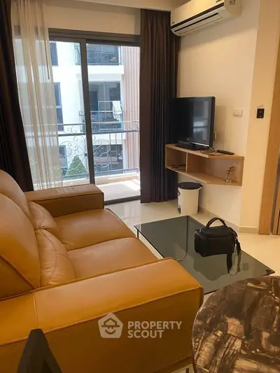 Modern living room with leather sofa, glass coffee table, and balcony view in a stylish apartment.