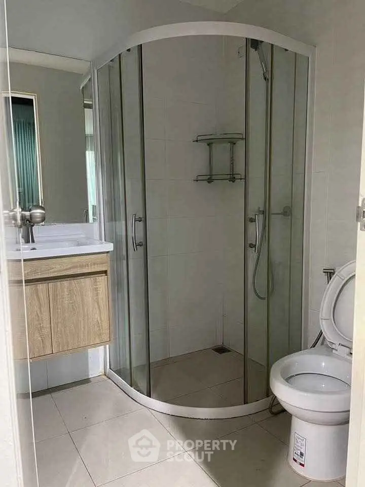 Modern bathroom with glass shower enclosure and sleek fixtures in a contemporary apartment.