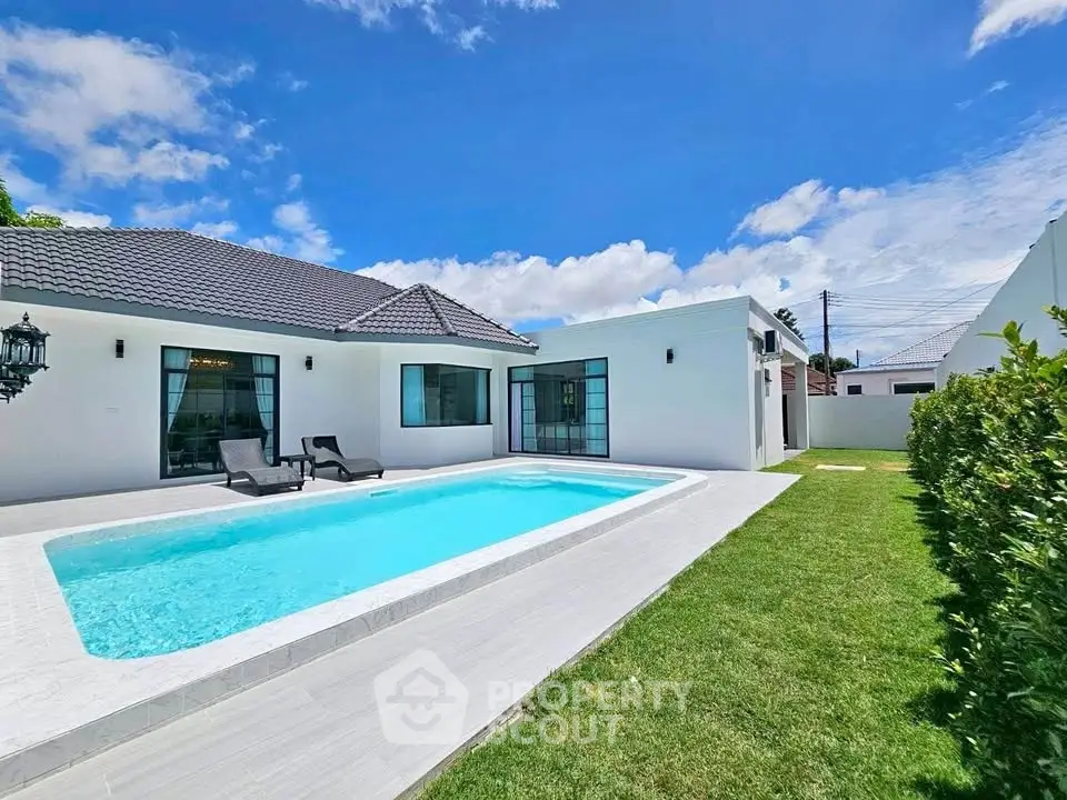 Stunning modern villa with private pool and lush garden under a clear blue sky.