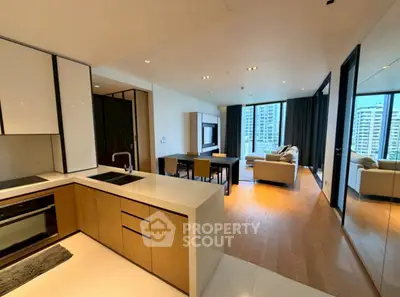 Modern open-plan living room with kitchen in luxury apartment, featuring sleek design and city views.