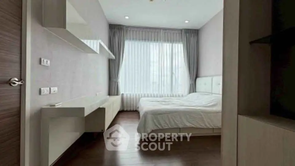 Modern minimalist bedroom with large window and sleek furnishings.