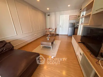 Modern living room with stylish decor and wooden flooring, featuring a cozy seating area and entertainment setup.